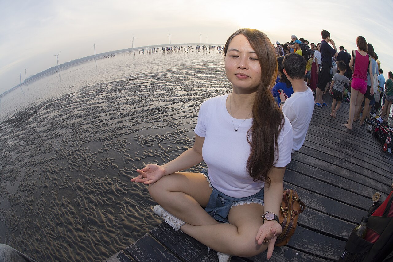 Woman sitting calmly in meditation beside open water
